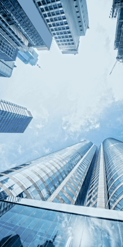 Glass office towers photographed looking upward against a pale sky