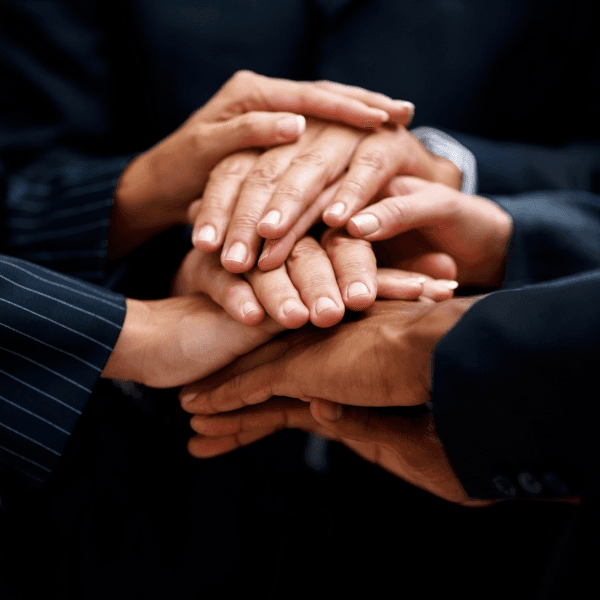 Colleagues in business dress joining hands over a table